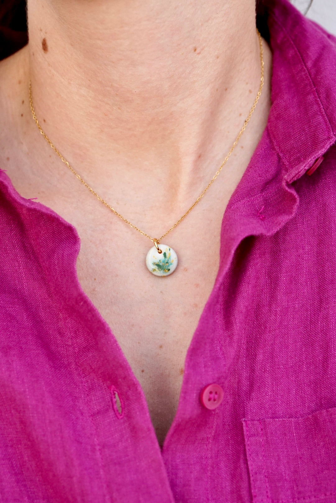 Pendientes Menorca verde en el cuello de una mujer con camisa morada